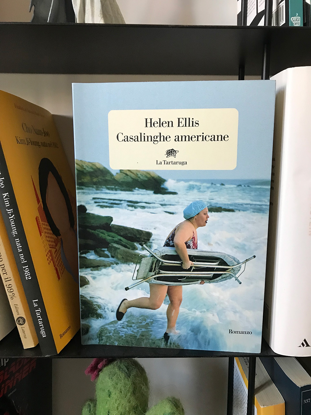 Copertina della raccolta di racconti Casalinghe americane di Helen Ellis: una donna in costume da bagno intero si appresta a fare surf con un asse da stiro sotto braccio.