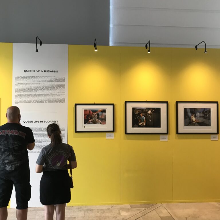 Un ragazzo e una ragazza guardano foto dei queen appese su un muro per una mostra, Queen a Budapest.