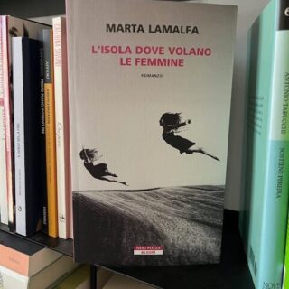 Un libro davanti a una libreria, nelal copertina due donne sembrano spiccare il volo